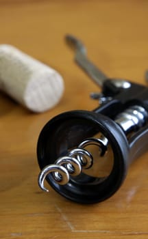 A corkscrew and a cork sitting on a wooden table.