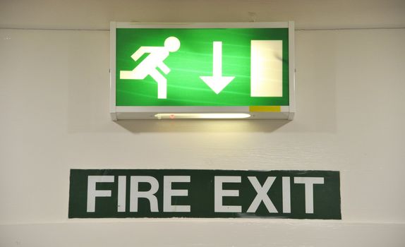 green and white warning sign glowing regarding fire exit emergency

