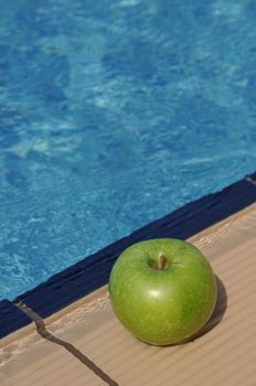 green apple at the pool side as a diet concept (healthy food and exercise)