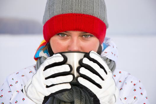 Young attractive woman drink hot tea from a mug in the winter.