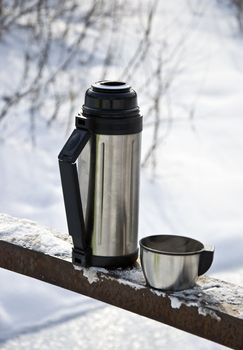 Metal thermos with hot tea drink. Winter.