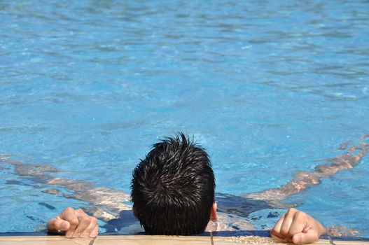 smiling young man doing water gymnastics (back view)