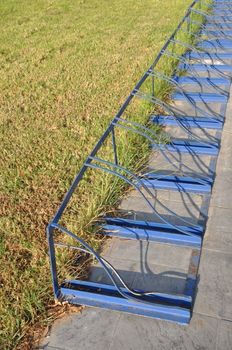 empty blue bicycle rack next to a green grass field
