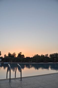 gorgeous resort swimming pool with umbrellas during sunset