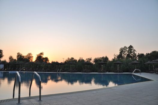 gorgeous resort swimming pool with umbrellas during sunset