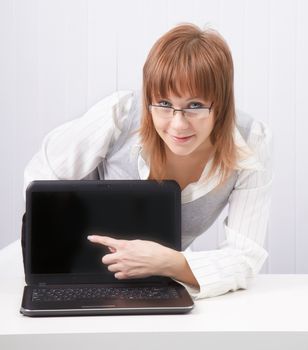 girl with glasses shows a finger on a laptop monitor. Close-up
