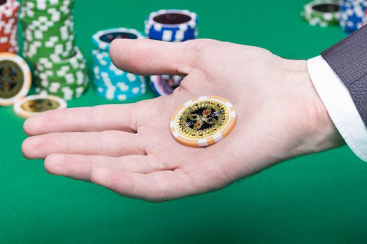 poker chips in the palm of a man on a background of green gambling table
