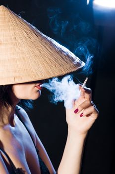 woman in the Vietnamese hat smoking a cigarette