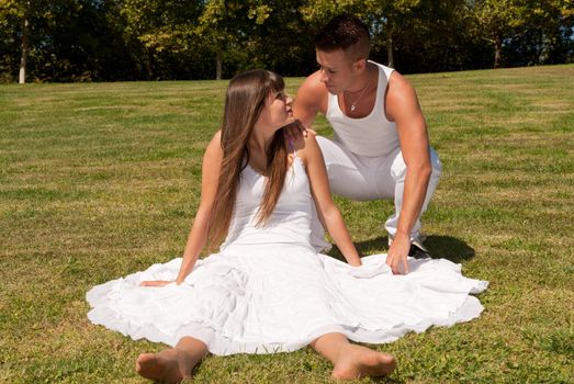 young couple happy sitting on grass white clothes, love relationship