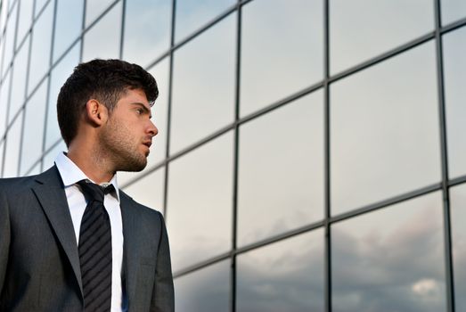 Young businessman looking good expectations on modern building background