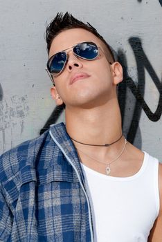 young male urban fashion sky on sunglasses over wall