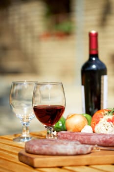 Still life with red wine and meat on table outdoors