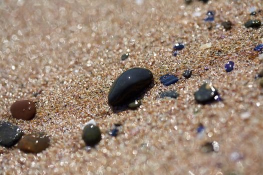 Wet round colorful stones at the sea shore