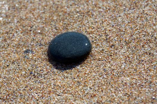 Black SPA stone on the beach sand