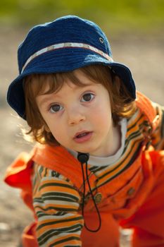 Little child, a cute boy with hat, playing at sunset