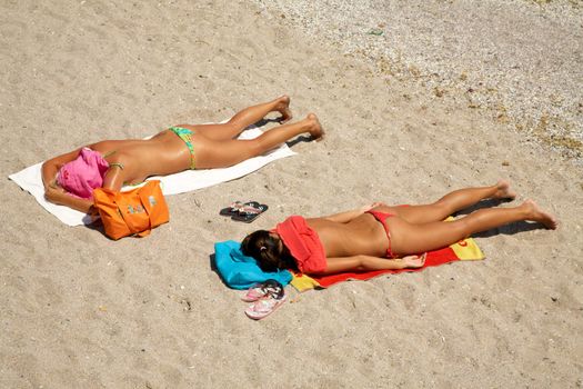 The girls taking sunbath on a beach sand