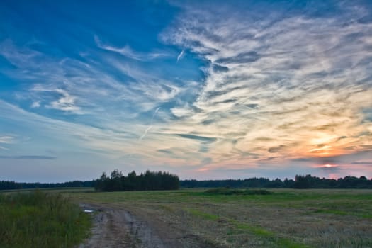 road in field at beautiful sunrise cloudscape