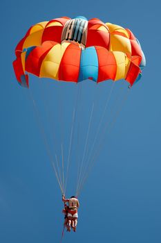 Two men flying with a colorful parachute