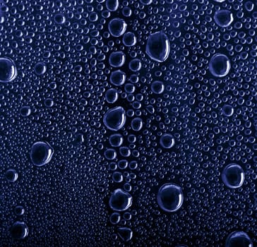 Shiny water drops on blue glass background