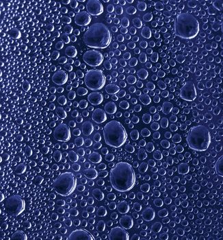 Blue water drops on glass background