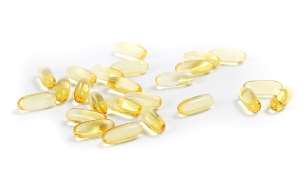 Transparent yellow cod-liver pills on a white background