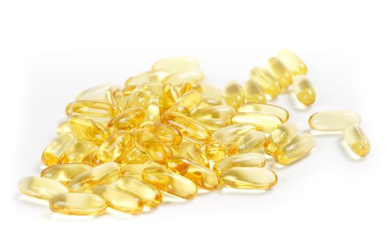 Transparent yellow cod-liver pills spilled on a white background