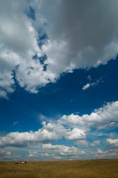 Landscape with little house, blue sky and clouds