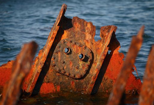 Rusty steel remains from an old ship uppear over the sea surface