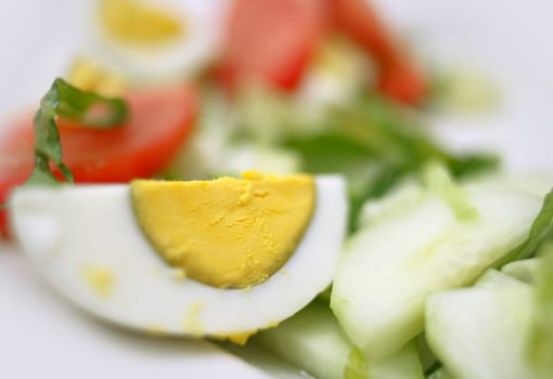 Slice of a boiled egg in a salad with cucumber and tomato