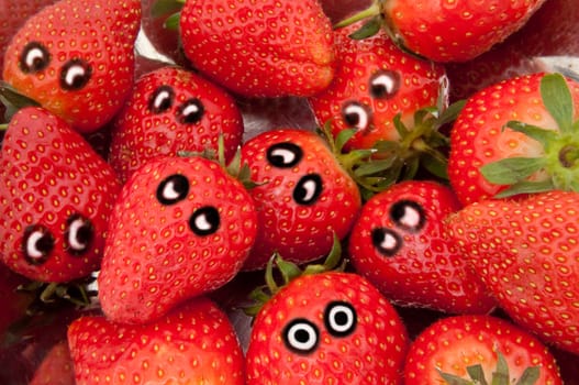 Close up on a group of fresh strawberries with painted eyes depicting different emotions