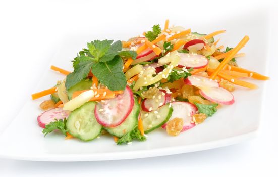 A salad of carrot, radish, cucumber, raisins, sesame and herbs