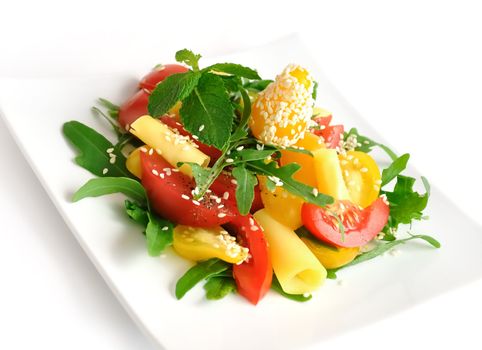 Salad of red and yellow tomato with cheese, arugula, sesame