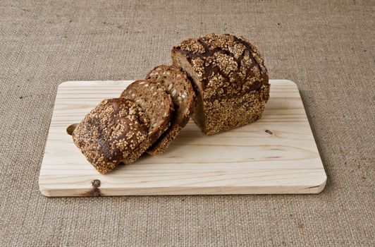 on the kitchen blackboard is sliced rye bread with grains on the background of coarse cloth
