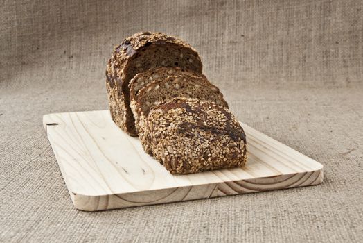 on the kitchen blackboard is sliced rye bread with grains on the background of coarse cloth