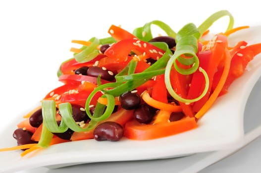 A salad of tomatoes, sweet peppers, red beans, carrots with sesame