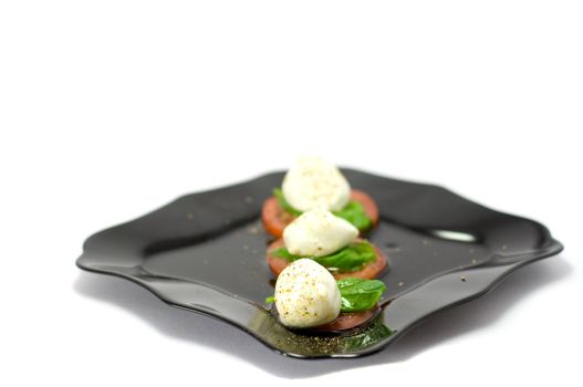 Caprese salad close-up with olive oil green basil and  pepper 