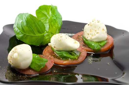 Caprese salad close-up with olive oil green basil and  pepper 