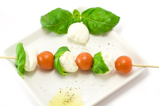 Caprese salad close-up with olive oil green basil and  pepper 