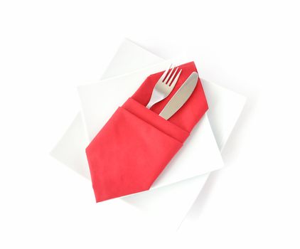 knife and fork in a red napkin on a white double square plate on a white background