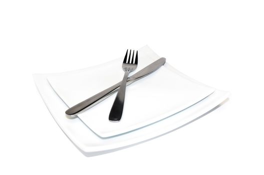 Knife and fork on a white plate isolated