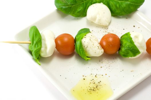 Caprese salad close-up with olive oil green basil and  pepper 