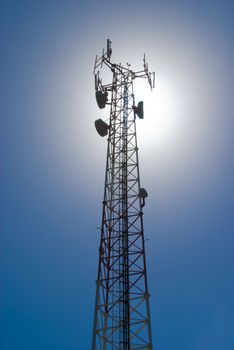 Cell tower and radio antenna back lit by sun