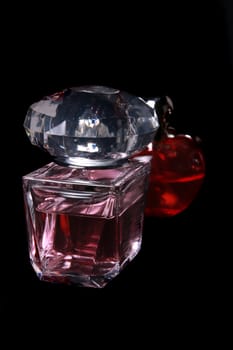 Beautiful perfume bottles in red and pink colors, on a black studio background.