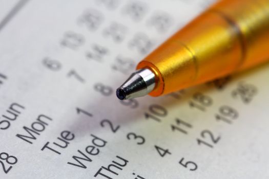 A yellow ballpoint pen on a white calendar page. Macro view, shallow dof. 