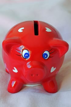 A cute red piggy bank decorated with hearts.