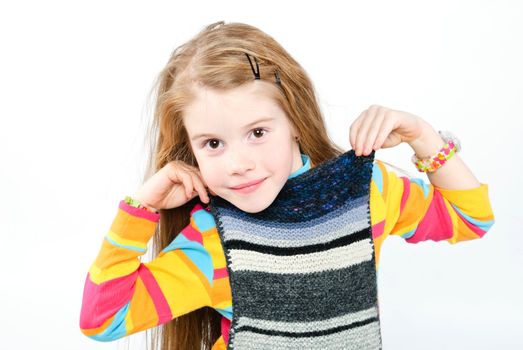 studio shot of pretty little girl trying on knitted scarf