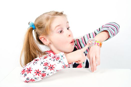 studio shot of pretty little girl pointing at her watch