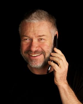 Man talking on cellphone and smiling on black background