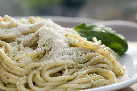 Gourmet pesto pasta dinner with fresh basil leaves.