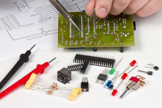 Engineer soldering circuit board surrounded by spare components